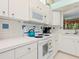 The kitchen has white cabinets, tile backsplash, and modern appliances with plenty of natural light at 6748 Hickory Hammock Cir, Bradenton, FL 34202