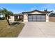 Inviting home featuring a spacious driveway leading to a garage, complemented by lush landscaping at 7145 Mamouth St, Englewood, FL 34224