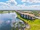 A long view of lakeside condo buildings with tile roofs and well-maintained landscaping, and a view of a golf course at 7705 Grand Estuary Trl # 202, Bradenton, FL 34212