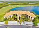 Stunning aerial view of the condo with golf course, lake, and parking; beautiful grounds with lush tropical landscaping at 7705 Grand Estuary Trl # 202, Bradenton, FL 34212