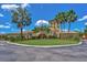 Elegant clubhouse featuring a circular driveway, manicured lawn, and vibrant landscaping at 7705 Grand Estuary Trl # 202, Bradenton, FL 34212
