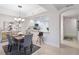 Bright dining room next to kitchen, with modern chandelier, table setting, and view to hallway at 808 3Rd W Ave # 203, Bradenton, FL 34205