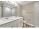 Bright bathroom featuring double sinks, sleek white cabinetry and shower with marble style tile at 8308 Pelican Rd, Englewood, FL 34224