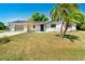 A charming home with a well-manicured lawn, a gray garage door, and a vibrant palm tree in the front yard at 8308 Pelican Rd, Englewood, FL 34224