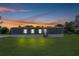 Exterior shot of home with lights on, showcasing its charming curb appeal against a beautiful sunset at 8414 Sweden Blvd, Punta Gorda, FL 33982