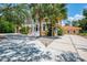 Two-story tan home with a spacious driveway, palm trees, and decorative white lion statues at 95 Vic Edwards Rd, Sarasota, FL 34240