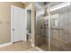 Well-lit bathroom with a glass-enclosed shower featuring tiled walls, seat, and convenient grab bar at 13721 Saw Palm Creek Trl, Lakewood Ranch, FL 34211