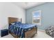 Cheerful bedroom featuring light blue walls, a wooden bed, and a bright window with plantation shutters at 13721 Saw Palm Creek Trl, Lakewood Ranch, FL 34211