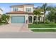 Charming home featuring a brick driveway, aqua garage door and shutters, red tile roof, and lovely landscaping at 13721 Saw Palm Creek Trl, Lakewood Ranch, FL 34211