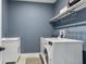 Functional laundry room in blue featuring modern washer and dryer, sink and wall mounted hanging rack at 13721 Saw Palm Creek Trl, Lakewood Ranch, FL 34211