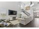 Open concept living area with soaring ceilings, a stylish staircase, and dark wood floors and large TV at 13721 Saw Palm Creek Trl, Lakewood Ranch, FL 34211