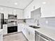 Modern kitchen featuring white cabinets, stainless steel appliances, and gray subway tile backsplash at 1709 N Tamiami Trl # 318, Sarasota, FL 34234