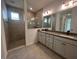 Well-lit bathroom with a walk-in shower, double vanity, and large mirror reflecting natural light at 19575 Fort King Run, Brooksville, FL 34601