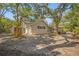 A charming home exterior is showcased with mature trees and a cozy outdoor seating area at 2072 Misty Sunrise Trl, Sarasota, FL 34240
