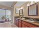 Bathroom featuring dual sinks with dark countertops, tile flooring, and access to a private outdoor area at 2072 Misty Sunrise Trl, Sarasota, FL 34240