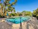 A refreshing pool surrounded by lush trees, lounge chairs, and seating with umbrellas at 2155 Wood St # B18, Sarasota, FL 34237