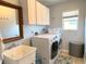 Functional laundry room with washer, dryer, sink, mirror and ample storage cabinets at 240 Patterson Ave, Osprey, FL 34229