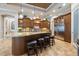 Charming kitchen island with stone countertops, a stainless steel fridge, and four barstools at 26725 Raphis Royale Blvd, Englewood, FL 34223
