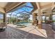 This outdoor space features a screened-in pool and spa, brick patio, outdoor kitchen, and lake views at 26725 Raphis Royale Blvd, Englewood, FL 34223