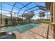The screened-in pool has a waterfall feature, brick pool deck, and beautiful views of the lake and palm trees at 26725 Raphis Royale Blvd, Englewood, FL 34223