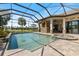 The screened-in pool and spa have lake views, a brick pool deck, and an outdoor kitchen at 26725 Raphis Royale Blvd, Englewood, FL 34223