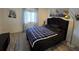 Bright bedroom featuring a black bed frame with a plush, blue plaid comforter and wood-look flooring at 3368 Lake Bayshore Dr # 217 Building P, Bradenton, FL 34205