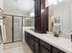 Bathroom featuring dual sinks, a frameless shower, and dark wood cabinetry at 3623 Pitch Ln, Sarasota, FL 34232