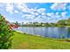 A picturesque lake view with a well-manicured lawn and vibrant red flowers at 4173 Westbourne Cir, Sarasota, FL 34238