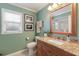 Bathroom with granite counters, wood cabinets, and a large framed mirror; bright window with blinds at 4211 73Rd E Ter, Sarasota, FL 34243
