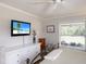 Bright bedroom featuring a ceiling fan, a mounted TV, and a sun-filled window with white wood blinds at 4211 73Rd E Ter, Sarasota, FL 34243