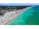 Vibrant aerial view of a beach packed with sunbathers, umbrellas, and crystal turquoise water near a busy beachside parking lot at 4307 Gulf Dr # 109, Holmes Beach, FL 34217