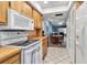 Bright kitchen featuring wooden cabinets, white appliances, and a tile floor that leads to a dining and living area at 4307 Gulf Dr # 109, Holmes Beach, FL 34217