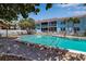 Community swimming pool with blue building backdrop, lounge chairs, and a quaint cabana at 4307 Gulf Dr # 109, Holmes Beach, FL 34217