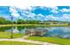 Lake view with a wooden dock, lush landscaping, and walking path offering serene outdoor enjoyment at 4325 Renwick Dr, Parrish, FL 34219