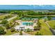 Aerial view of the community pool area featuring a playground, clubhouse, and nearby lake surrounded by green spaces at 4325 Renwick Dr, Parrish, FL 34219