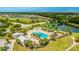 Aerial view of a community pool with splashpad, playground, and modern clubhouse surrounded by palm trees and lush landscaping at 4325 Renwick Dr, Parrish, FL 34219