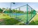 Fenced tennis court featuring well-maintained playing surface, net, and surrounding landscape at 4570 Pinebrook Cir # 406, Bradenton, FL 34209