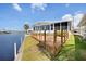 Waterfront home featuring a wooden deck, neat lawn, and water views, ideal for outdoor enjoyment at 520 Ideal Pl, North Port, FL 34287