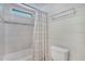 Cozy bathroom featuring tiled walls, updated toilet, and a shower/tub with a striped curtain and small window at 520 Ideal Pl, North Port, FL 34287