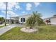 Well-kept home with landscaped lawn, decorative palm, and covered parking, presenting a welcoming facade at 520 Ideal Pl, North Port, FL 34287