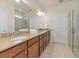 Bathroom featuring granite counters, warm cabinets, dual sinks, and a glass shower at 5952 Snowy Egret Dr, Sarasota, FL 34238