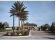 View of the community entrance with palm trees, a landscaped median, and classic architectural details at 5952 Snowy Egret Dr, Sarasota, FL 34238