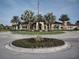Community entrance featuring a circular driveway, palm trees, and well-manicured landscaping at 5952 Snowy Egret Dr, Sarasota, FL 34238