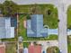 Aerial view of a blue single-story home with a gray roof, surrounded by lush greenery and neighboring properties at 6004 10Th Ave W, Bradenton, FL 34209