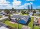 Backyard view featuring a blue single-story home with a sunroom, patio, partial fencing, and surrounding neighborhood at 6004 10Th Ave W, Bradenton, FL 34209