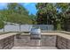 A gorgeous outdoor kitchen made of stone with stainless steel appliances and a built-in grill on a stone patio at 6015 S Elkins Ave, Tampa, FL 33611