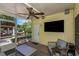 Comfortable outdoor seating and TV in a screened patio with direct access to the backyard at 6015 S Elkins Ave, Tampa, FL 33611