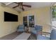Relaxing screened patio featuring wicker furniture, a mounted TV, and a ceiling fan at 6015 S Elkins Ave, Tampa, FL 33611
