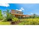 Back exterior view of a two story home with a covered patio, lush landscaping, and a dark metal fence at 6111 Horse Mill Pl, Palmetto, FL 34221
