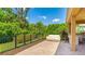 Paver patio with built-in outdoor kitchen, adjacent seating area, and beautiful green surroundings with black metal fence at 6111 Horse Mill Pl, Palmetto, FL 34221